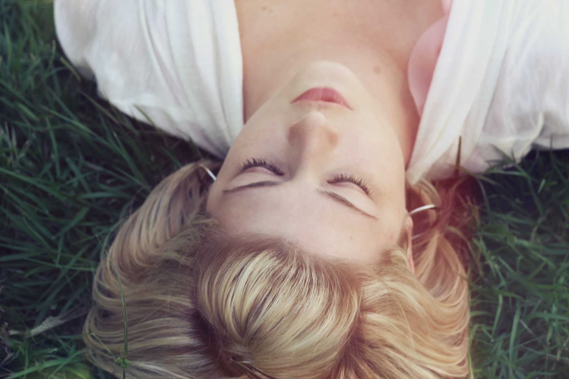 Head-shot of a woman, lying down on grass at rest